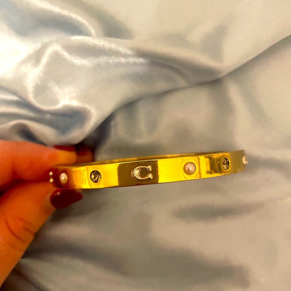 Signature hinge bangle by Coach in gold